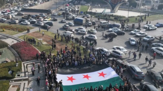 La gente celebra sosteniendo una gran bandera de la oposición siria en la Plaza de los Omeyas en Damasco el 9 de diciembre de 2024.